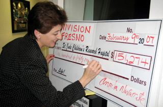 Univision Fresno general manager Angela Navarrete signs the check signifying the amount the station raised
