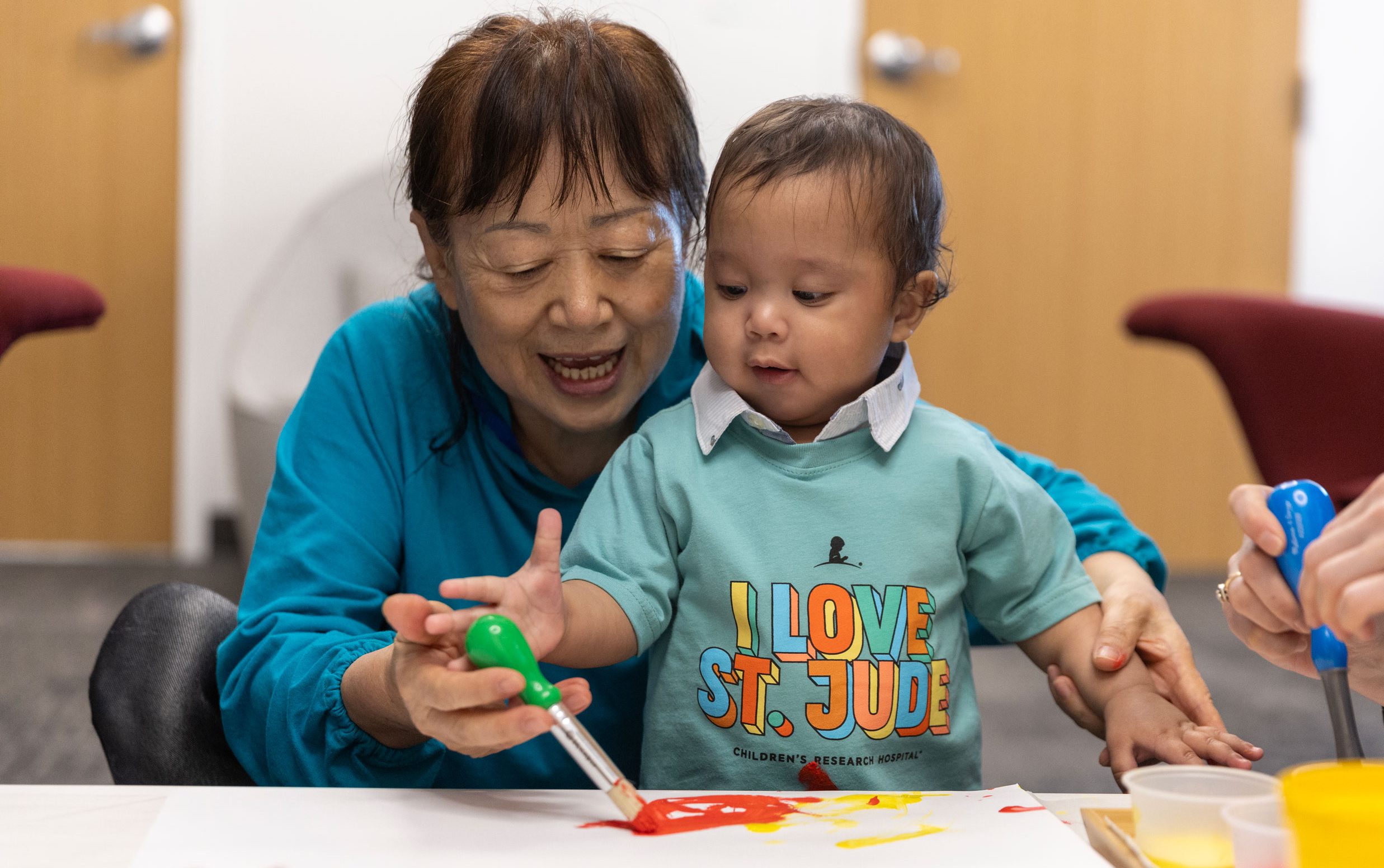 St. Jude patient Han is painting during art therapy with a family member.
