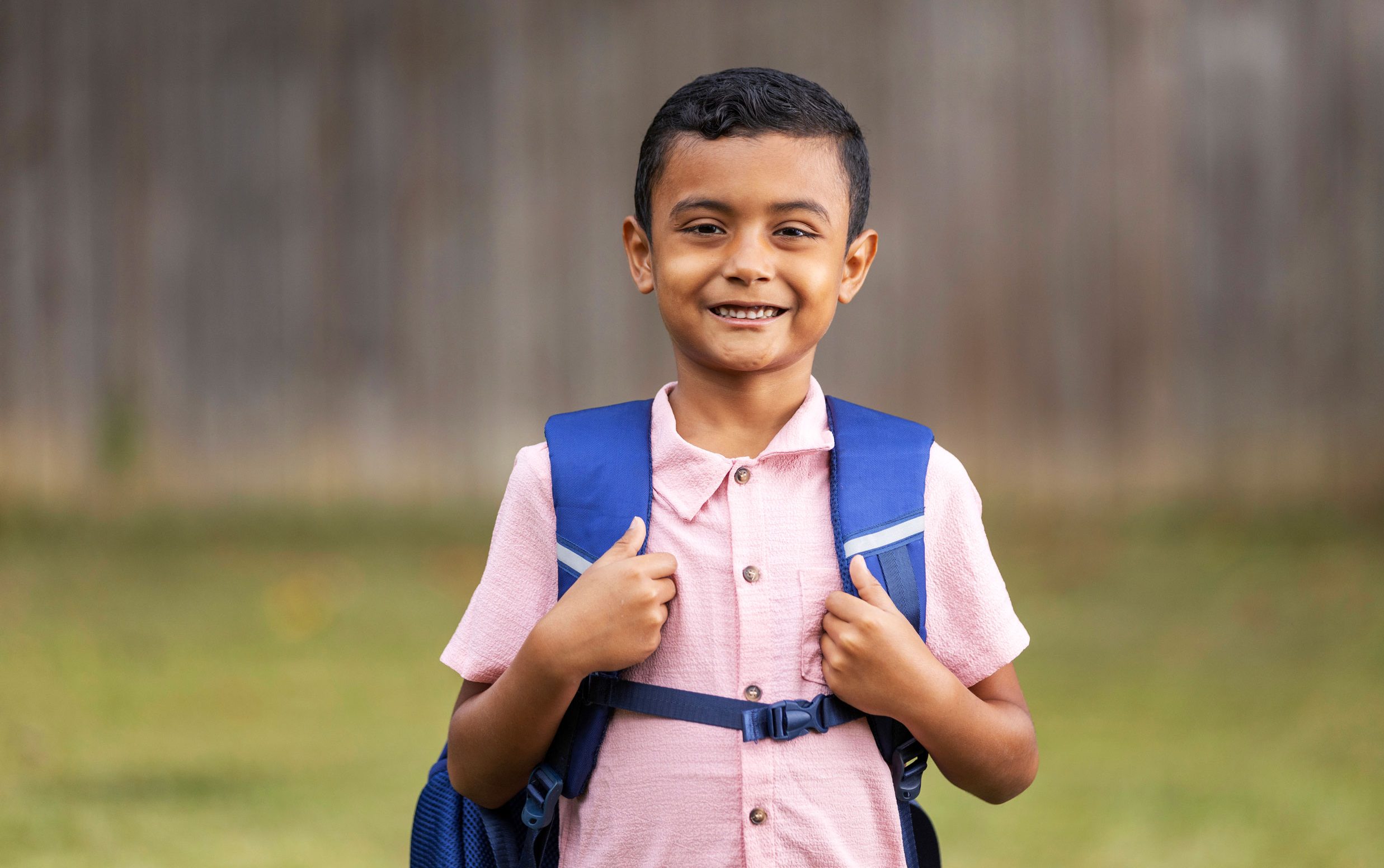 Patient Franser wears a backpack and smiles outdoors.