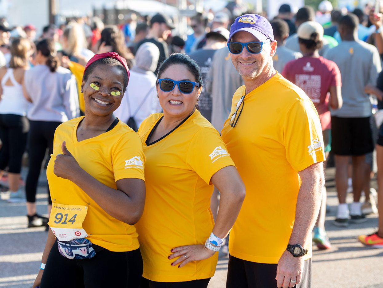 memphis-walk-run Three participants in the St. Jude Walk/Run smile and pose for the camera wearing gold T-shirt for Childhood Cancer Awareness Month,
