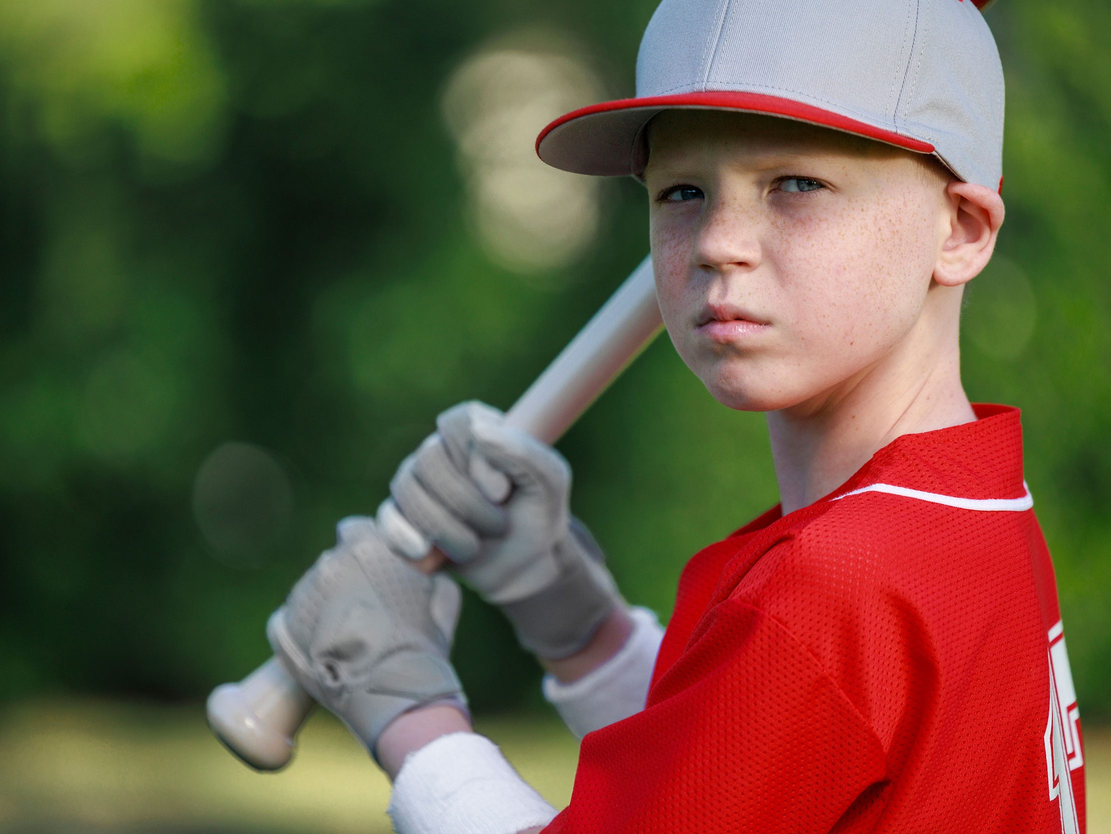 St. Jude patient Maddox wears a baseball uniform and cap and holds a baseball bat.