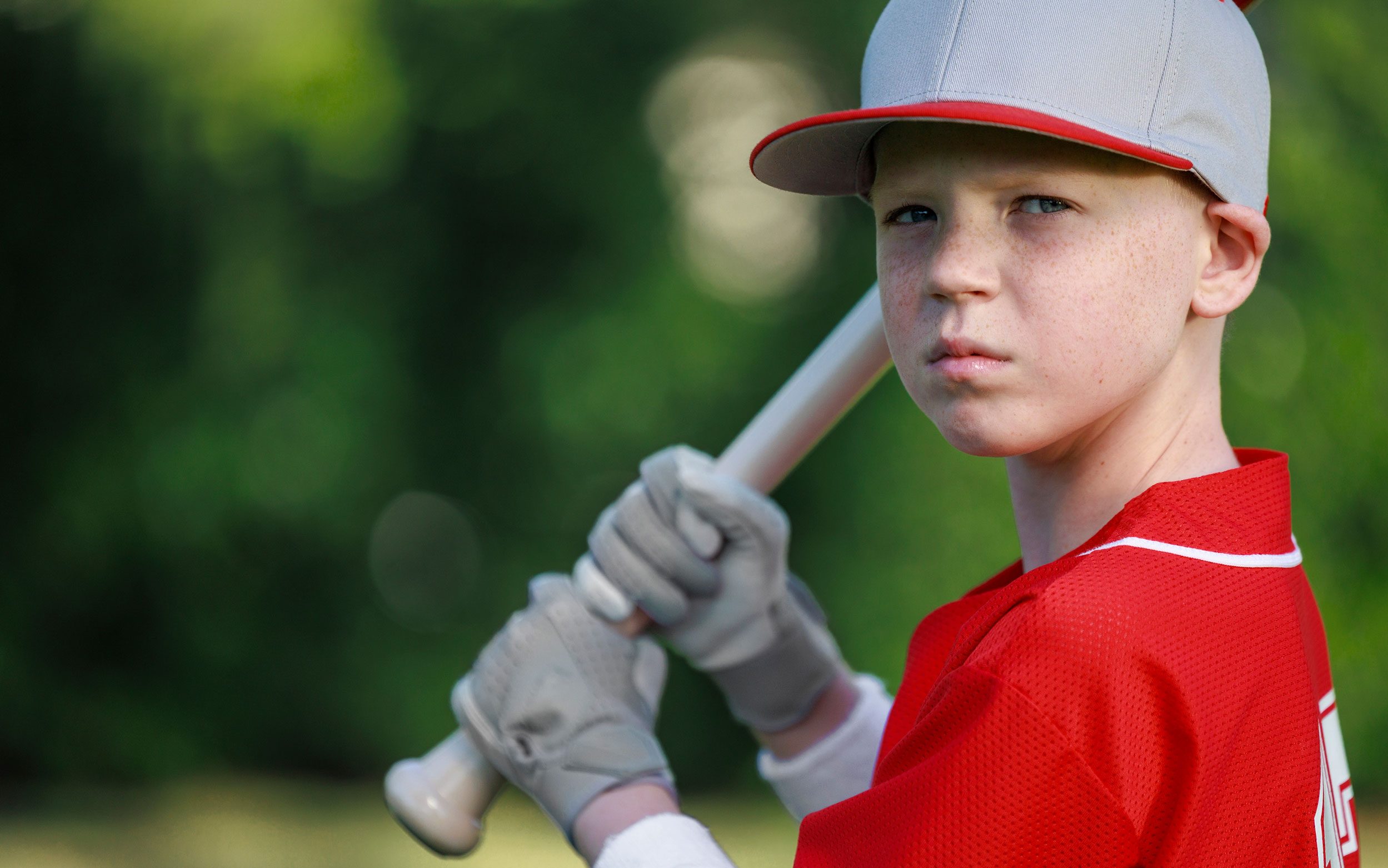 St. Jude patient Maddox wears a baseball uniform and cap and holds a baseball bat.