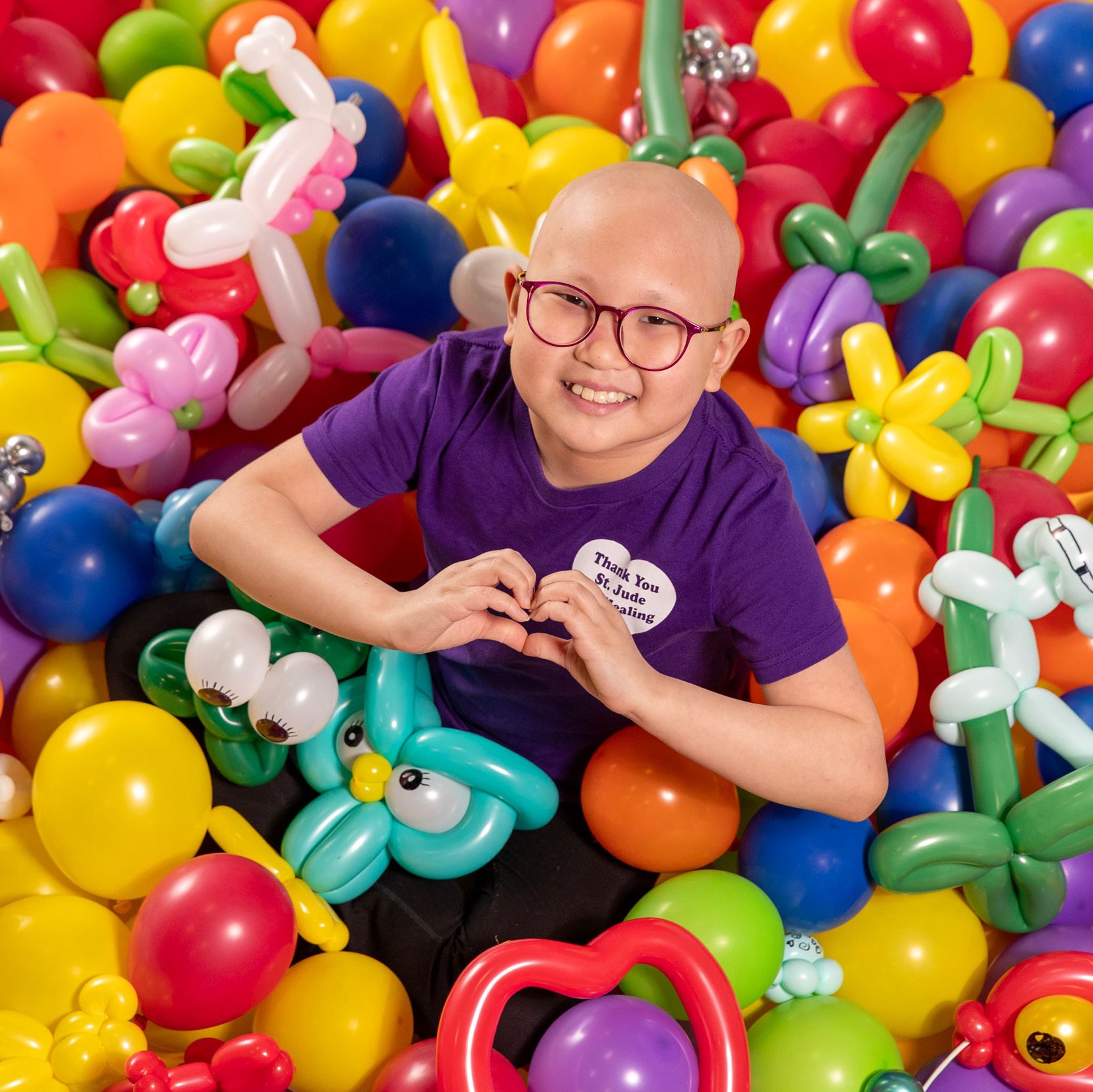 St. Jude patient Misheel makes a heart sign with her hands in this overhead photo taken with her balloon art creations.