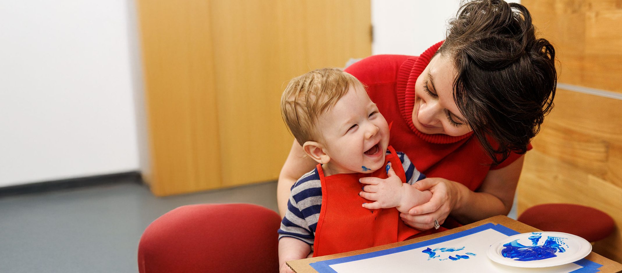 Patient Avelino paints while sitting in his mom's lap.