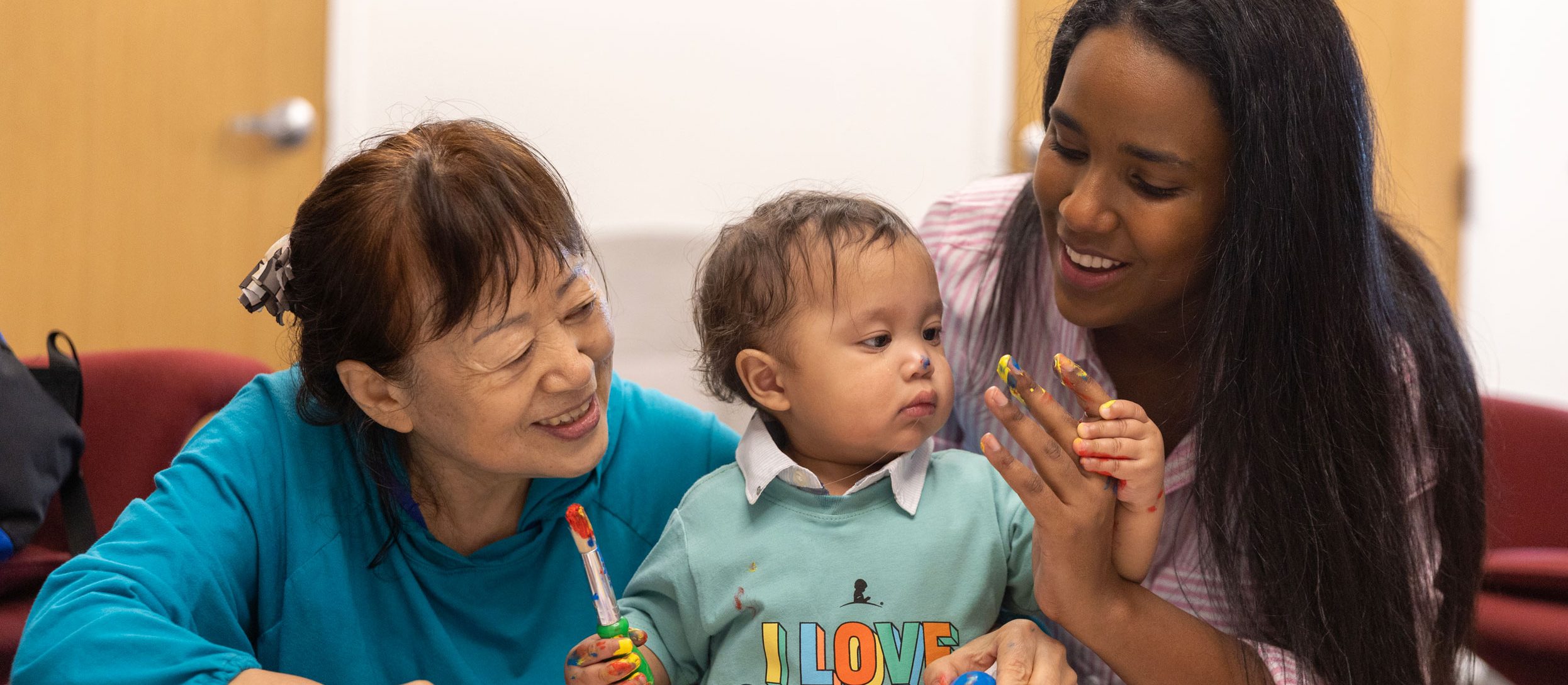 St. Jude patient Han paints a picture with the help of his mother and grandmother.