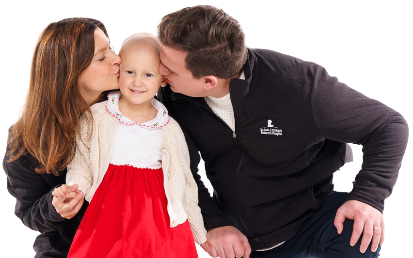 St. Jude patient Sully gets kisses from her mom and dad in a holiday-themed studio portrait.