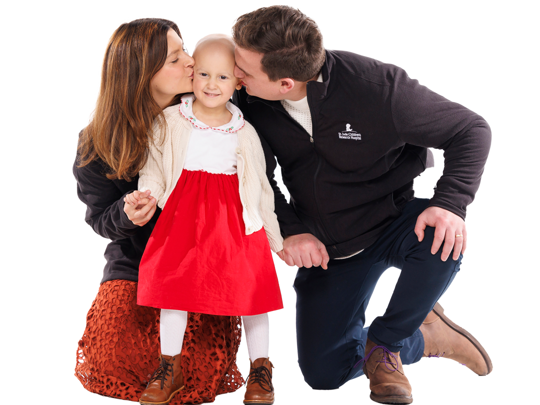 St. Jude patient Sully gets kisses from her mom and dad in a holiday-themed studio portrait.