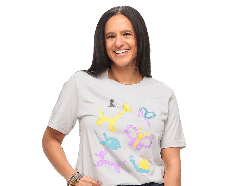 A woman with long dark hair wears a St. Jude T-shirt with colorful balloon shapes on it.