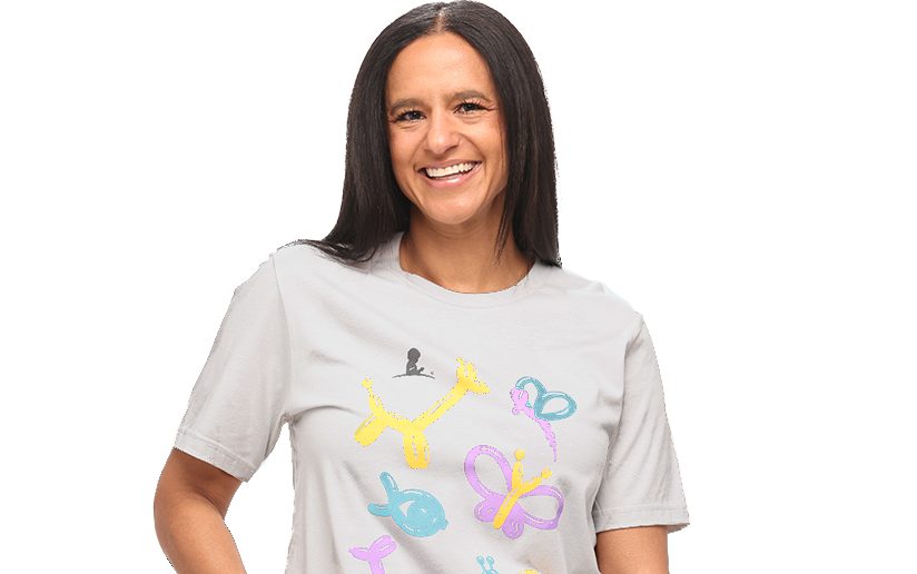 A woman with long dark hair wears a St. Jude T-shirt with colorful balloon shapes on it.