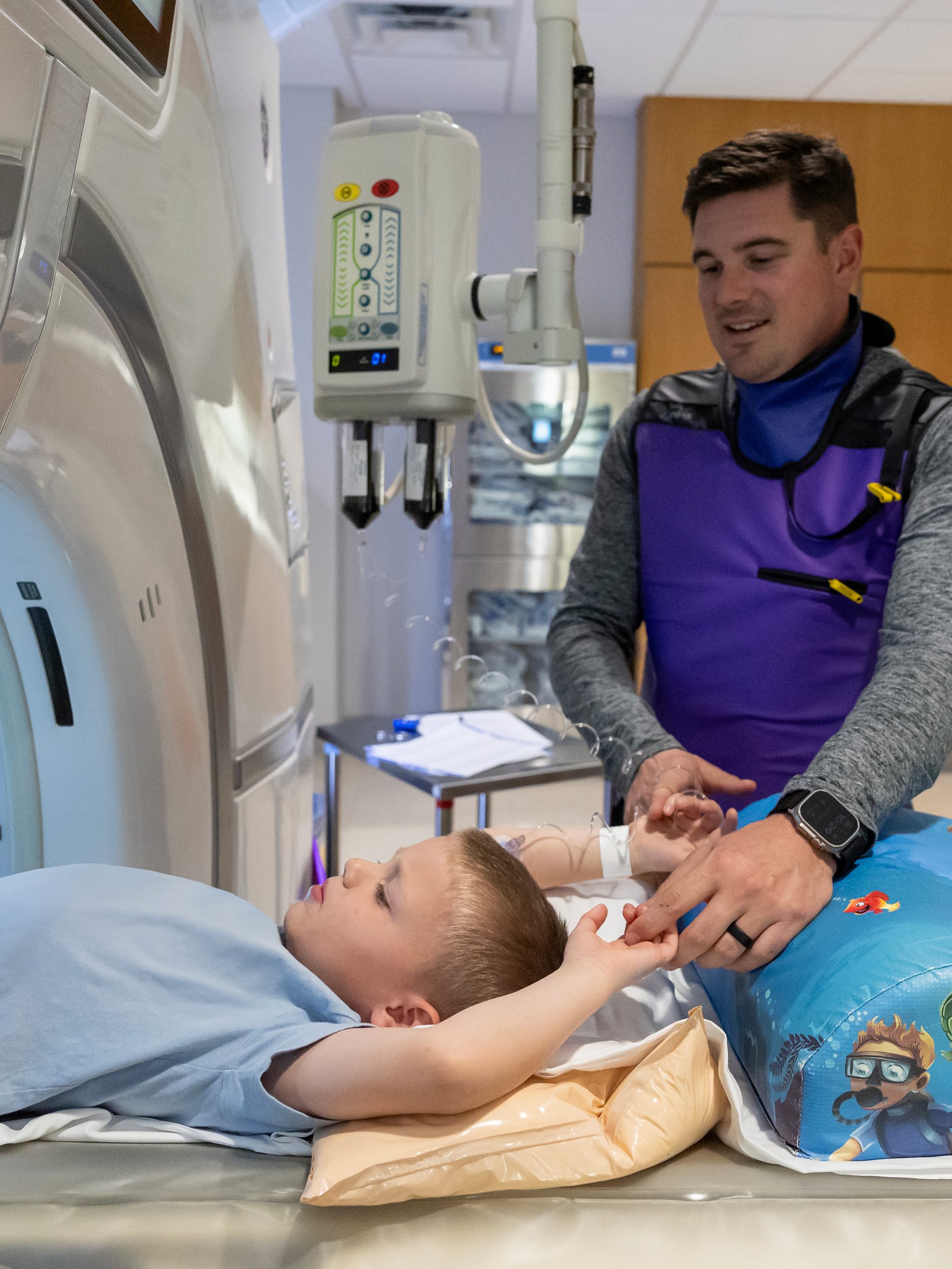 St. Jude patient Hunter holds his dad's hand before a CT scan