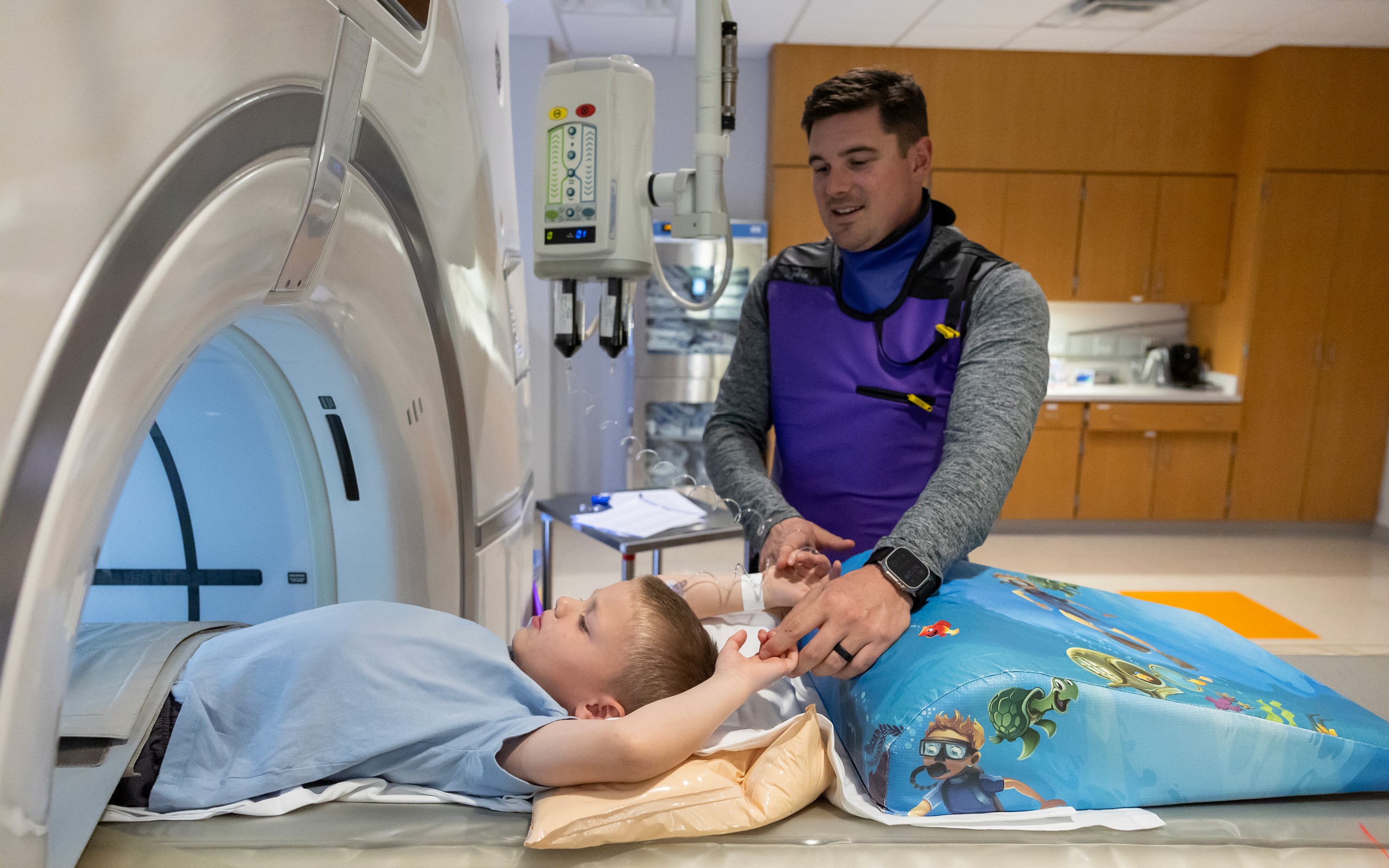 St. Jude patient Hunter holds his dad's hand before a CT scan
