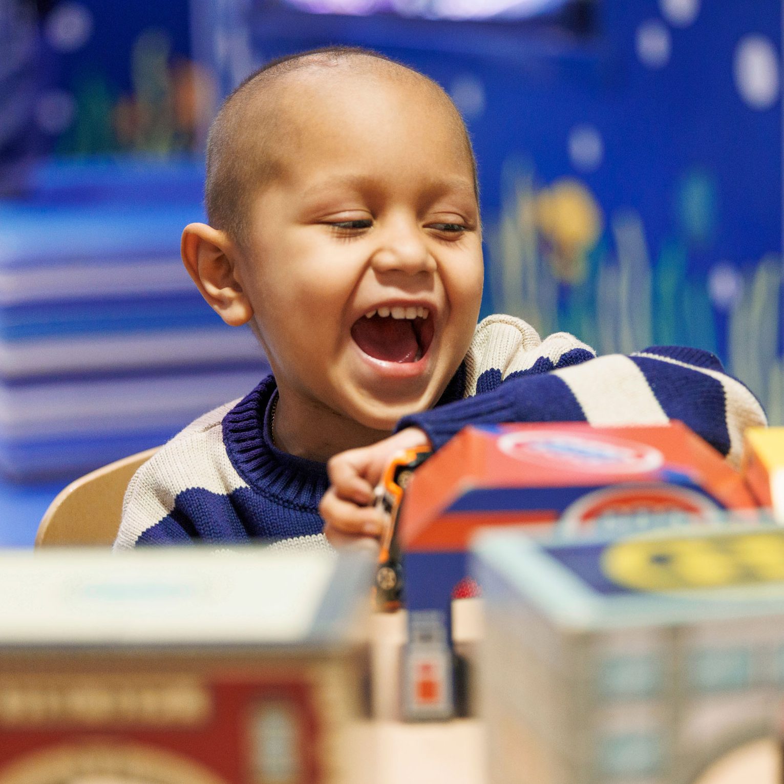 Leonel, paciente hispano de St. Jude, sonriendo mientras juega en un cuarto del hospital. 