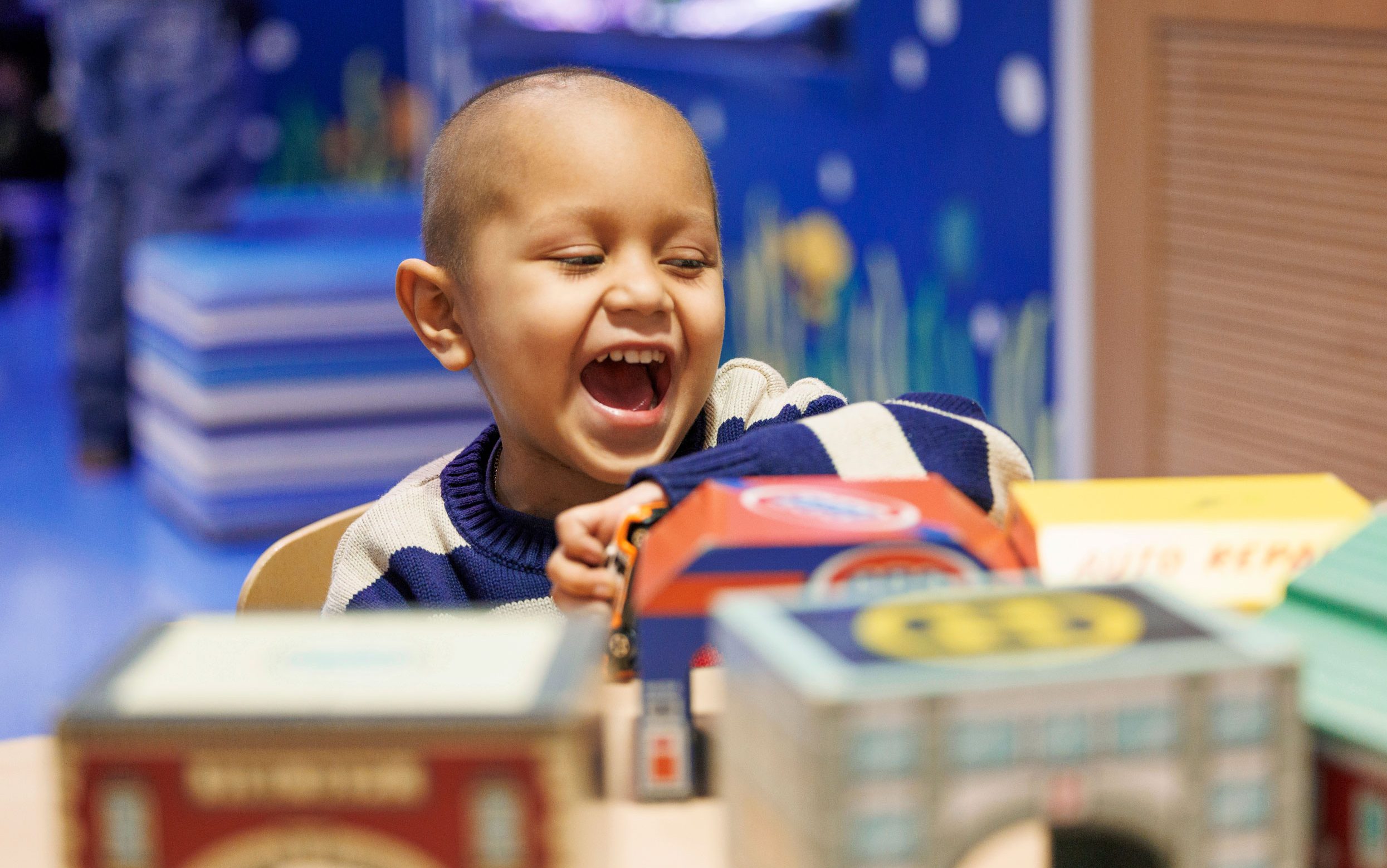 Leonel, paciente hispano de St. Jude, sonriendo mientras juega en un cuarto del hospital.