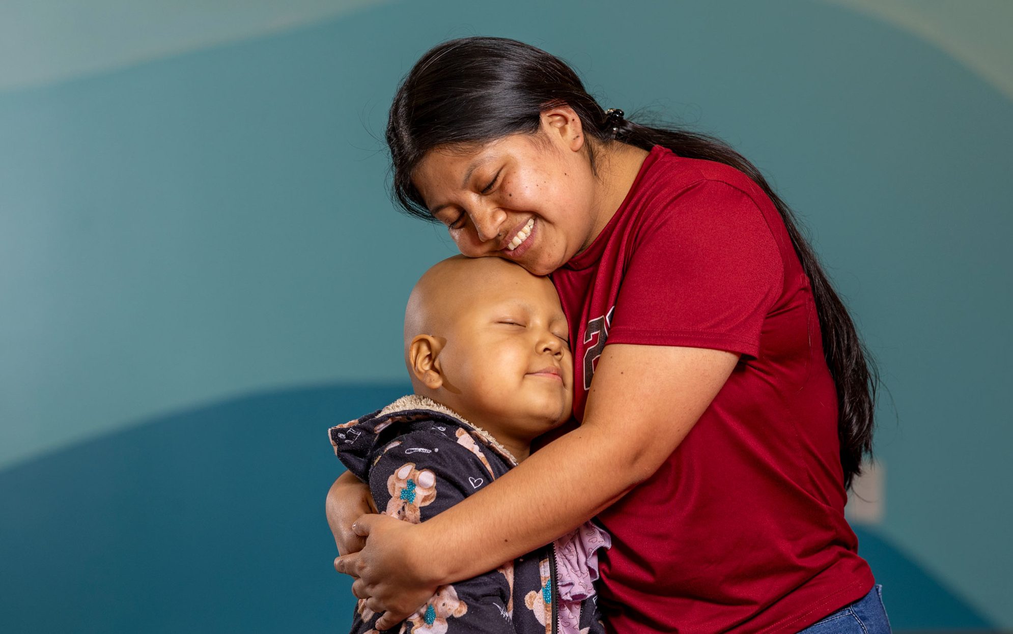 Valentina, paciente hispana de St. Jude, abrazando a su mamá.