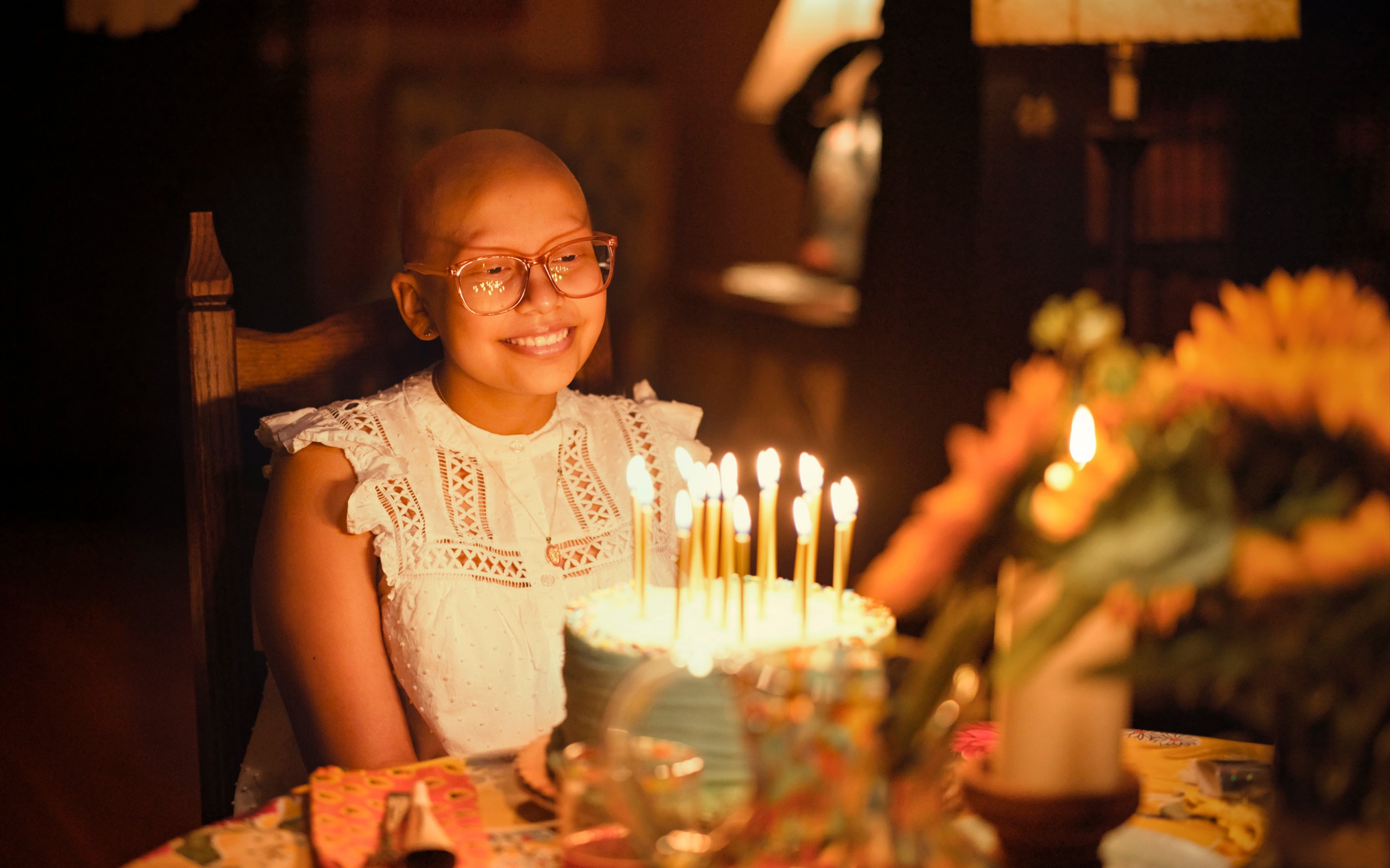 Aylin, paciente de St. Jude, frente a un pastel de cumpleaños.