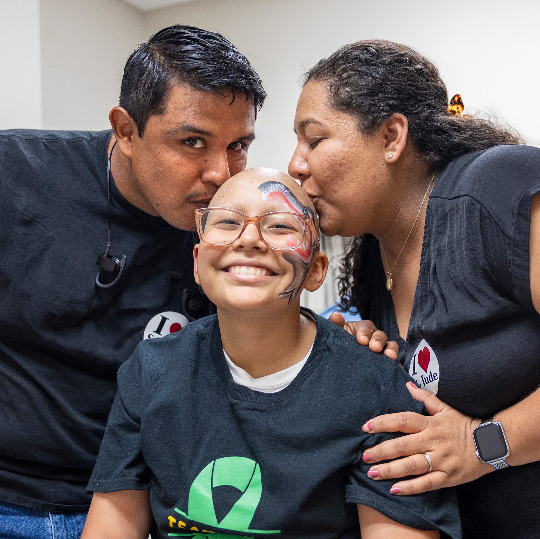 Aylin, paciente de St. Jude, recibe un beso de sus padres.