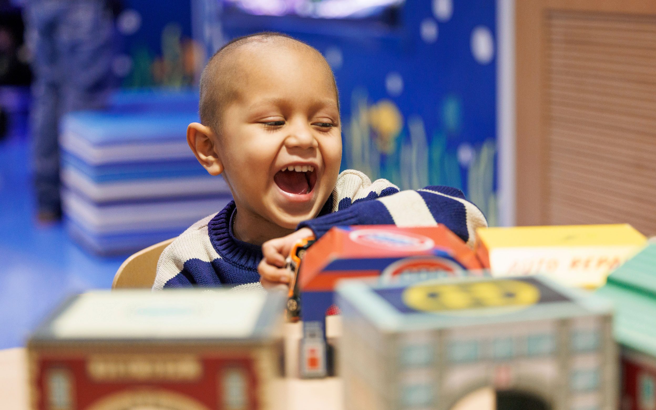 Leonel, paciente hispano de St. Jude, sonriendo mientras juega en un cuarto del hospital.