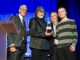 Randy Owen accepting an award on stage with a St. Jude patient and Richard Shadyac, Jr.