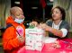 Debra Stamps, an administrative assistant in Patient Business Services, assists Randall with wrapping a gift.