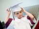 A child adjusts his graduation cap.