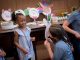 A girl holds up her mask while another girl laughs.