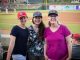 Dr. Kim Nichols poses with two women in front of the baseball field.