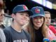 A mother and son smile while watching the baseball game.