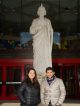 A woman and a man standing in front of the St. Jude Thaddeus statue