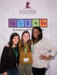 Three girls pose in front of the Science Scholars sign
