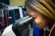 A science scholar looks through a microscope