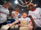 A blindfolded member brother on the orange team puts together a wooden puzzle.