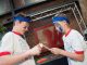 Two sibling brothers participate in an event using chopsticks to pass a marshmallow to each other.