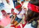 A red team member gets her face painted.