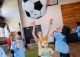 Children bounce a giant soccer ball in teh air.