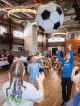 Siblings bounce a giant soccer ball in the air.