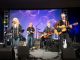 Kim Carnes and her band play on stage.