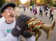 A man playing the trumpet for runners passing by.