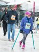 A girl using walking canes crosses the finish line.