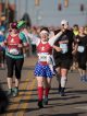 A half marathon runner holds her arms up in victory as she completes the race.