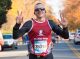 A half marathon runner holds up peace signs as he passes the photographer.