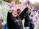 A girl with pom-poms cheers on the runners as they pass by.