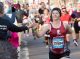 A half-marathon runner high-fives an onlooker as she runs.