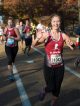 A marathon runner smiles and waves at the camera as she runs through midtown Memphis.