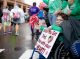 A St. Jude patient cheers on runners holding a sign that says "When you get tired, run with your Heart!"