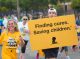 Walkers holding up a sign that says "Finding cures. Saving children."