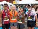 Four runners smile with their medals.