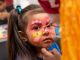 A little girl gets her face painted.