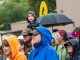 A child rides on his parents shoulders while walking the race in the rain.