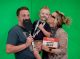 A family poses with silly props in front of a green screen.