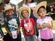 Three children smile together in cowboy outfits.